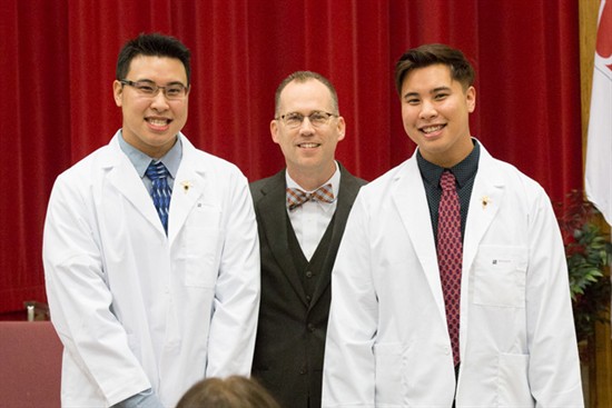 President Joseph Stiefel with two students at white coat ceremony