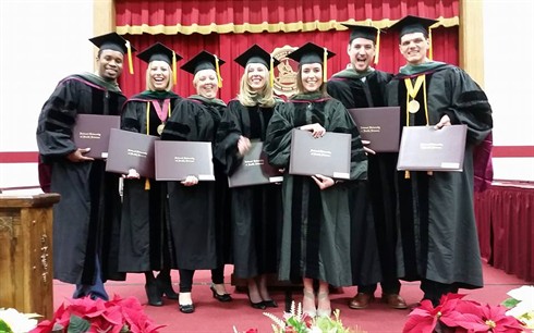 december graduates holding diplomas
