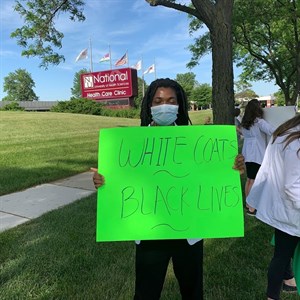 NUHS student demonstrator holding White Coats Black Lives sign