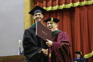 President Stiefel and graduate pose with diploma