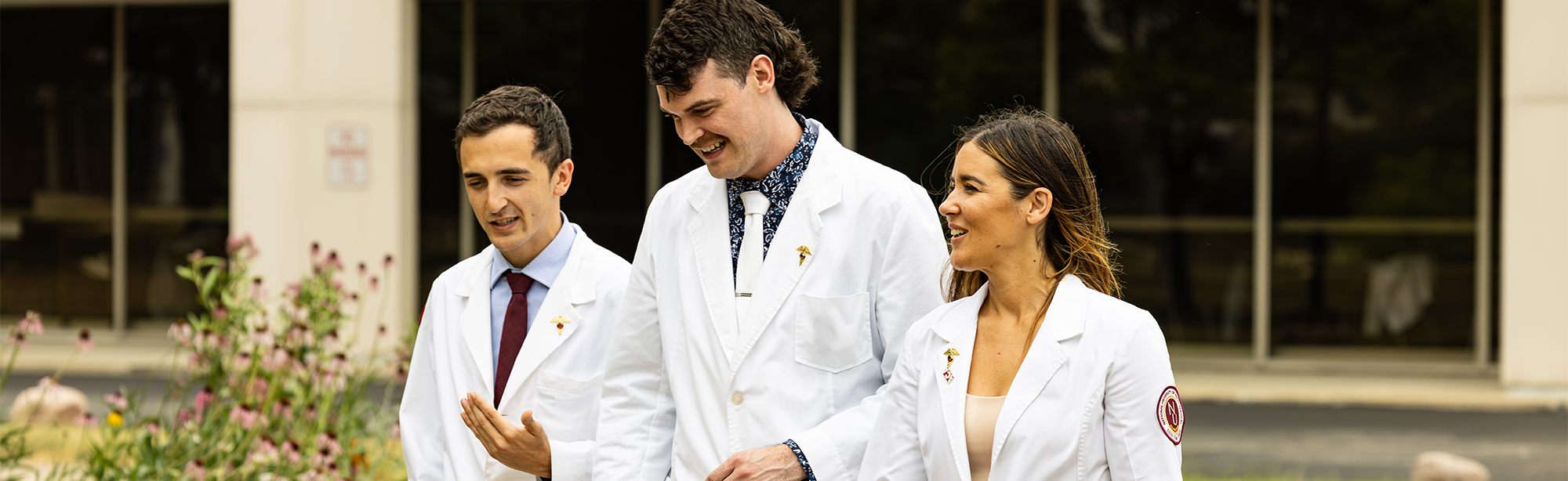 students in white coats walking around campus