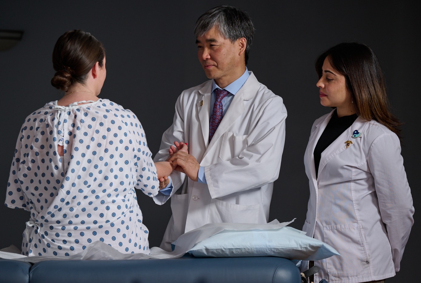Acupuncture patient, clinician and intern consult for treatment.