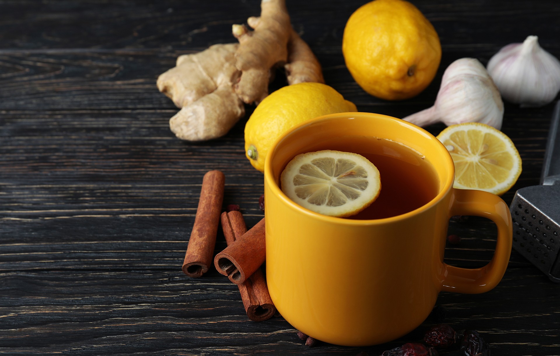 Cup of hot tea with lemon, cinnamon, garlic on the side