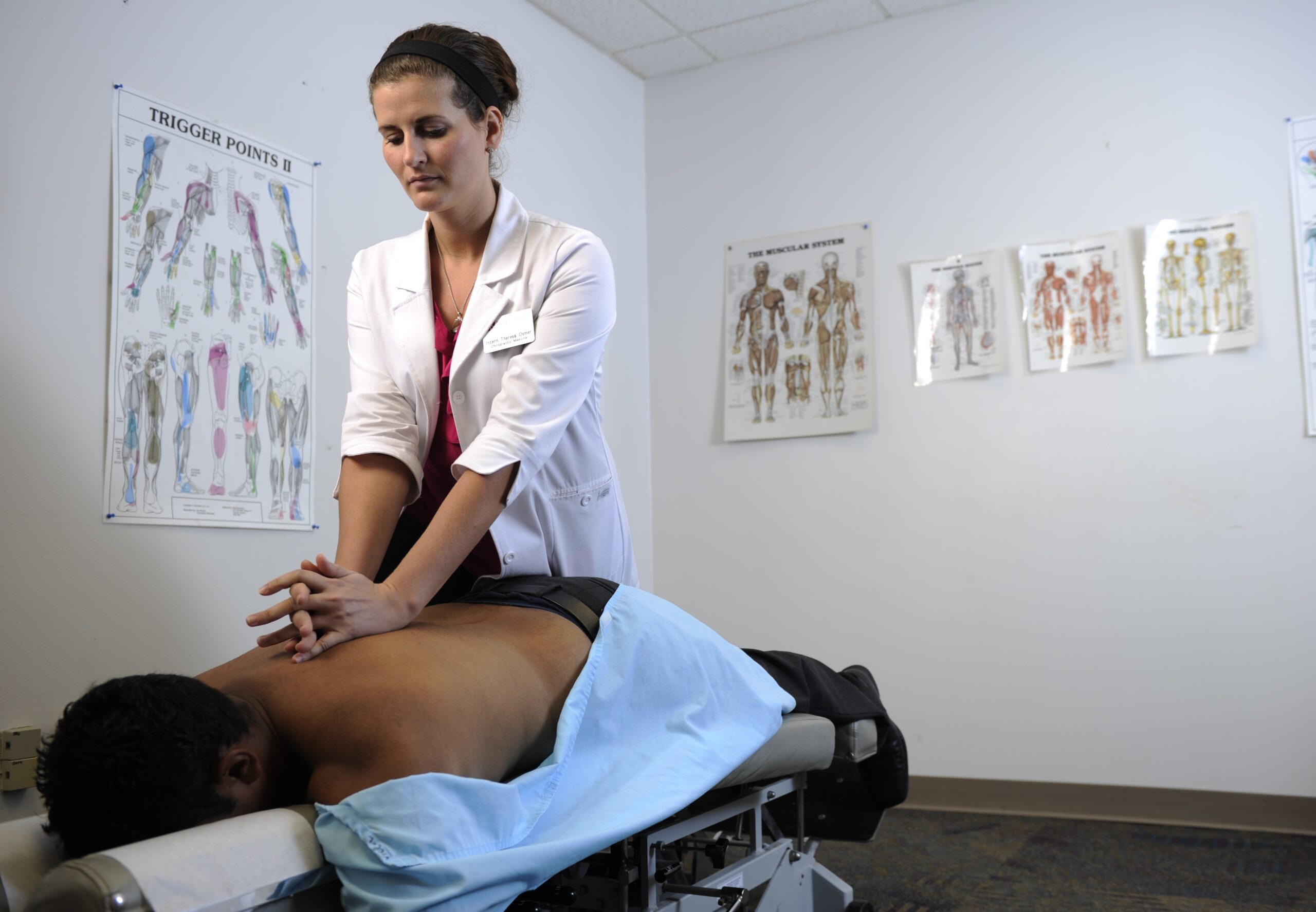 Female DC intern adjusting back of male patient