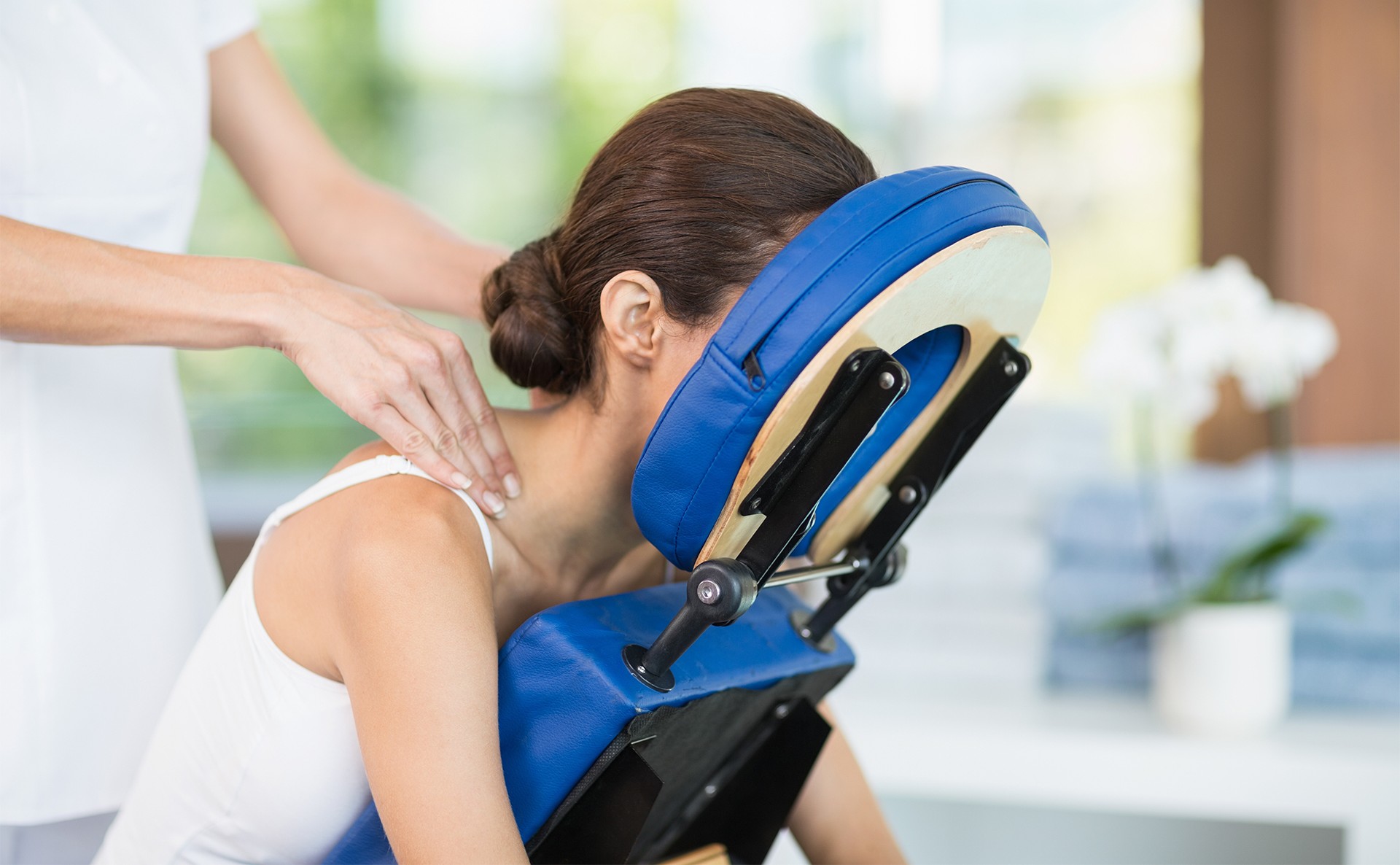 Female patient in therapy chair receiving neck massage