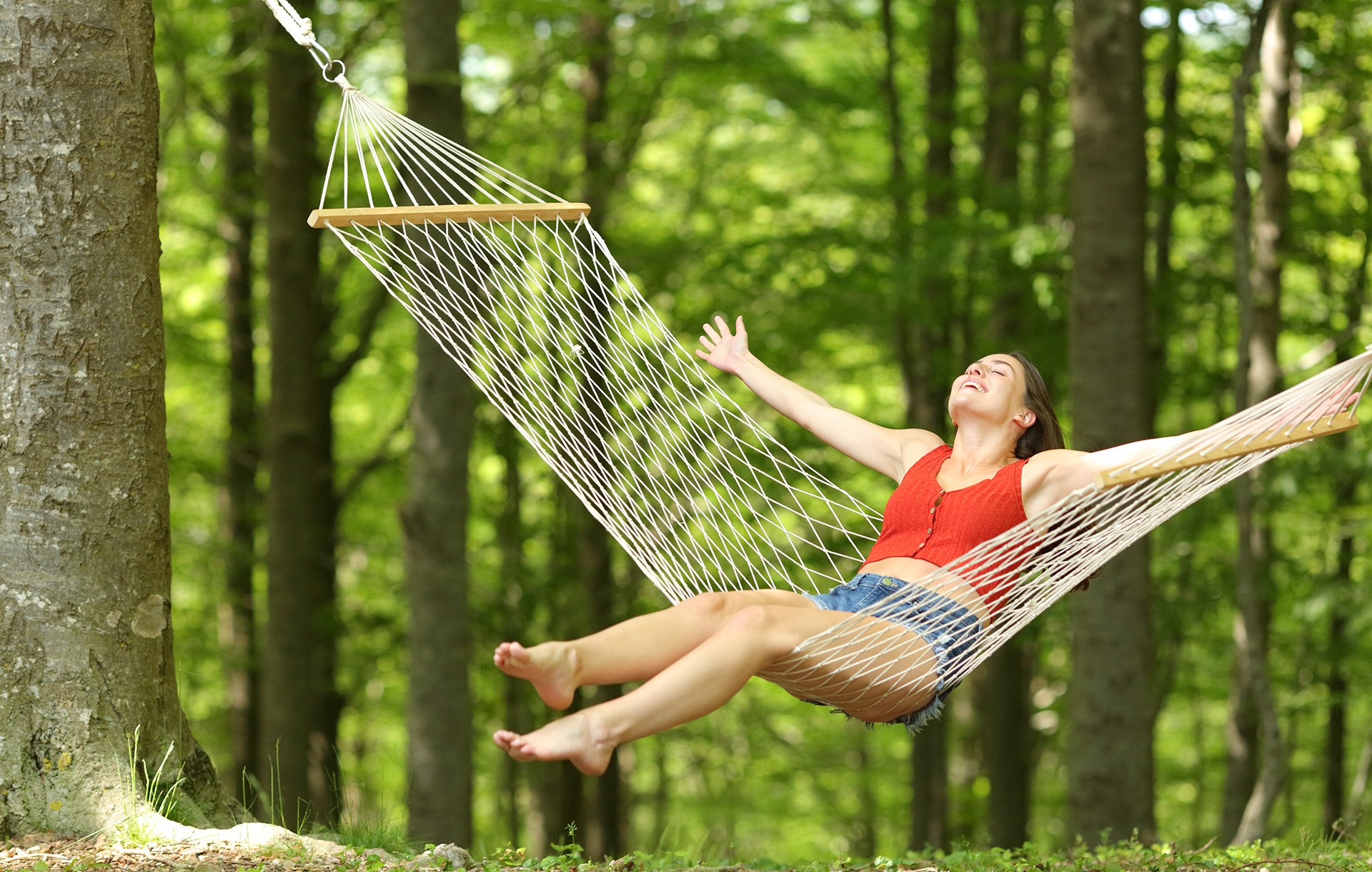 Happy female relaxing on hammock in wooded setting