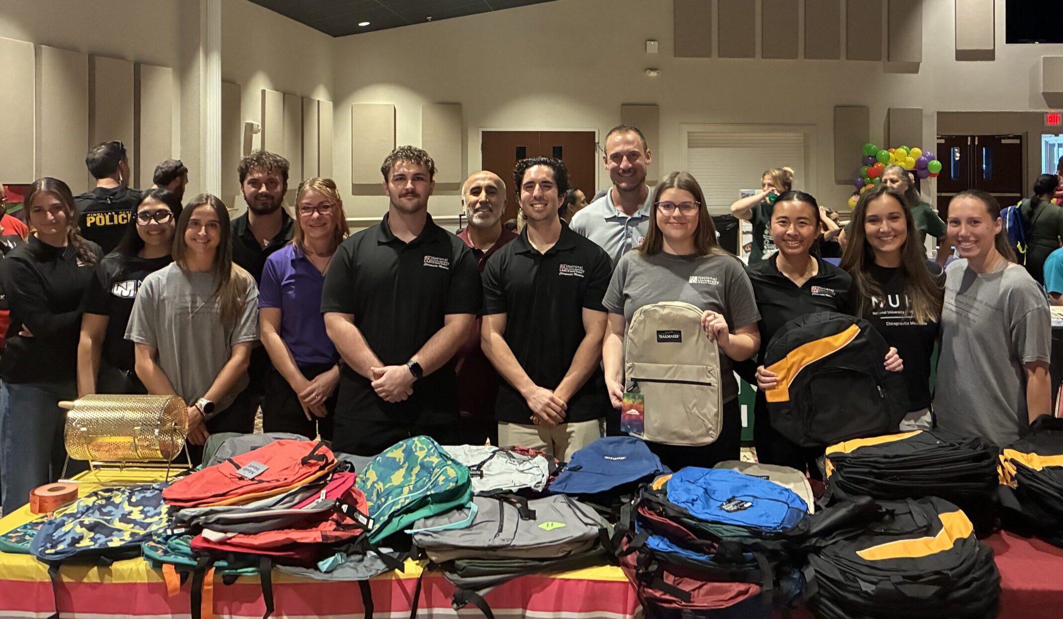 Volunteers pose in front of a table of backpacks