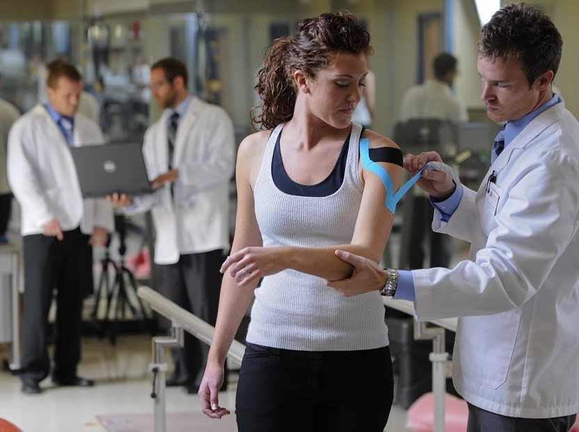 Male DC intern Kinesio taping shoulder of female patient
