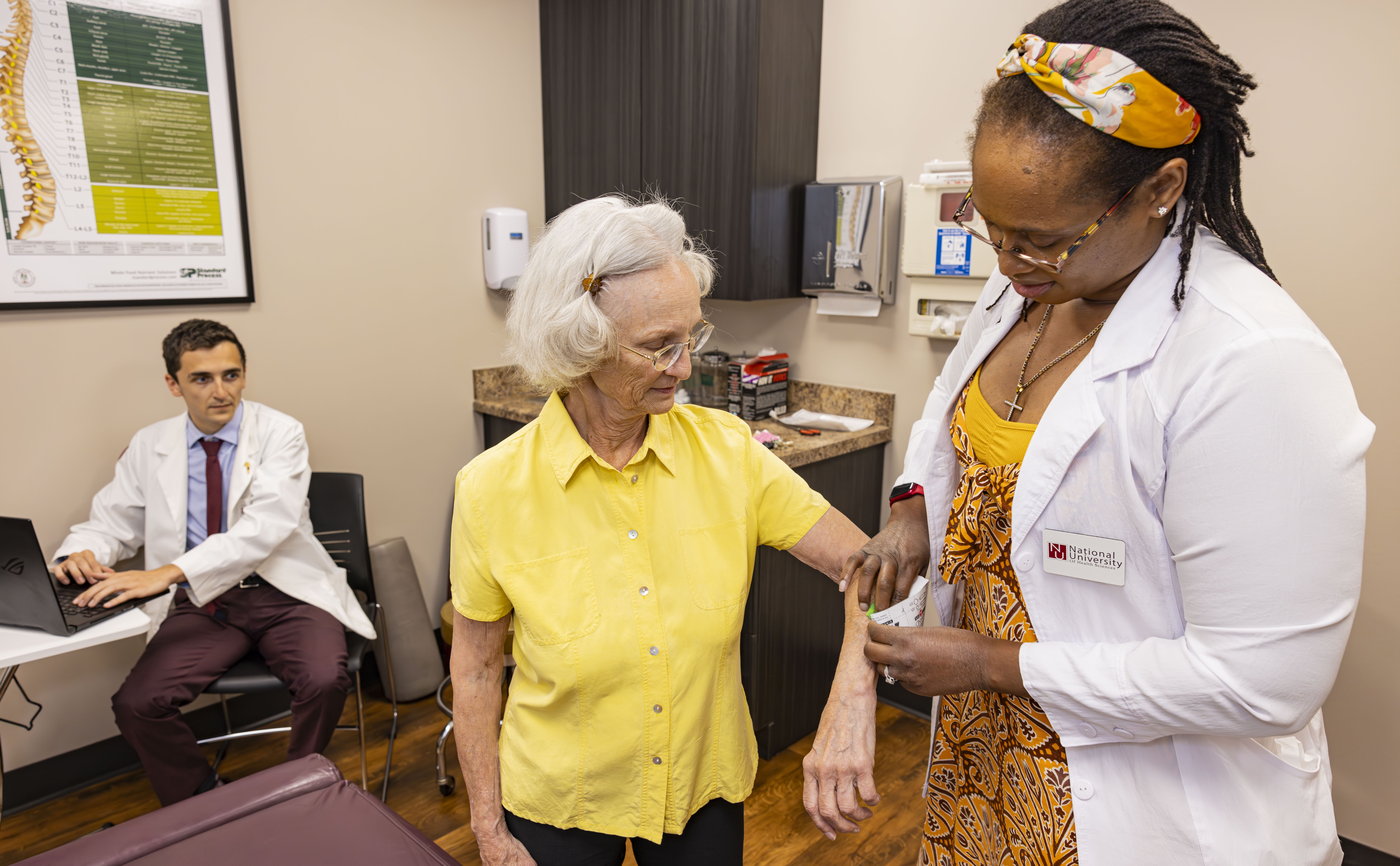 Mature female patient with male and female chiropractic interns receiving treatment