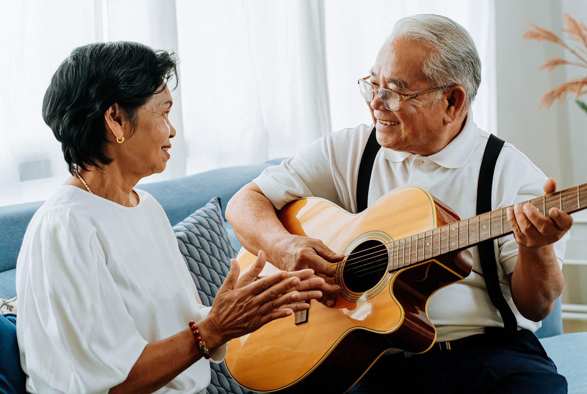 Middle aged Asian couple playing guitar