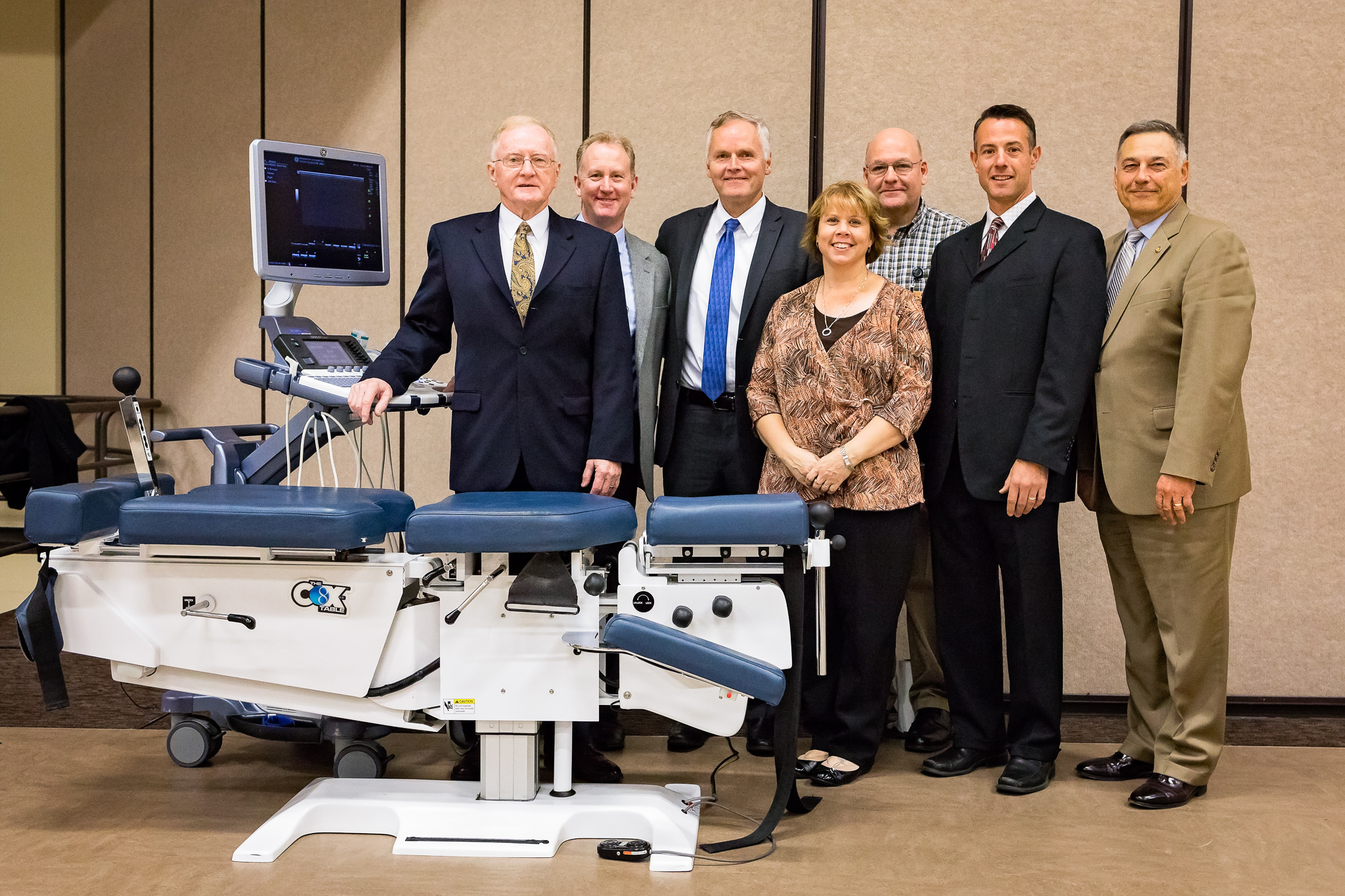 James M. Cox, DC, DACBR, FICC, Hon.D.Litt., FACO(H); Ralph Kruse DC, FIANM; George Joachim, DC, DABCR; and Kurt Olding, DC, FICC, FIANM, stand next to a Cox® Table at NUHS with Tracy McHugh, MBA, NUHS Vice President for Administrative Services, William Bogar, DC, DACBR, NUHS Chair of Diagnostic Imaging and Residency, and Randy Swenson, DC, MHPE, NUHS Vice President for Academic Services.