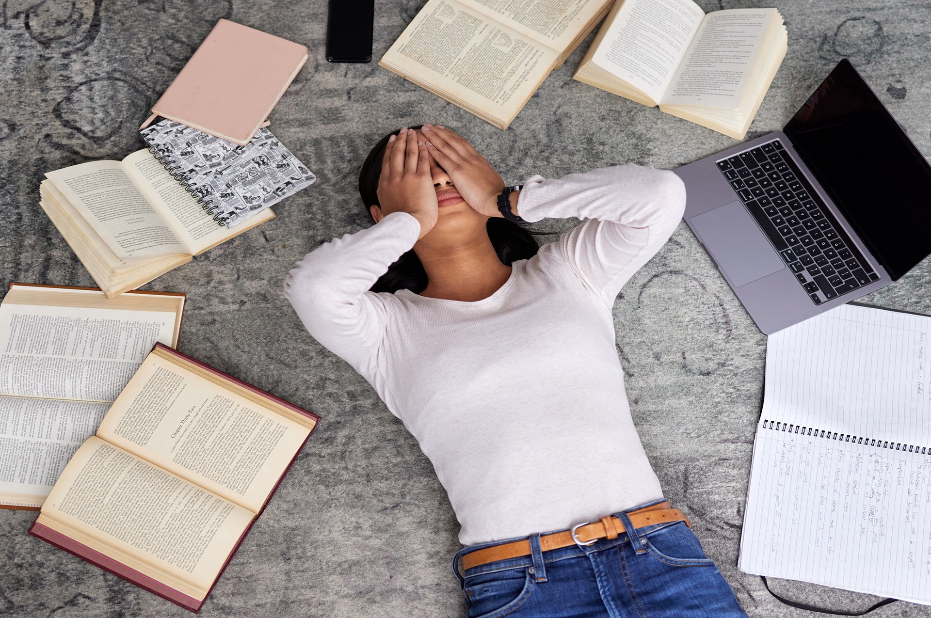 Stressed out female student surrounded by laptop and books